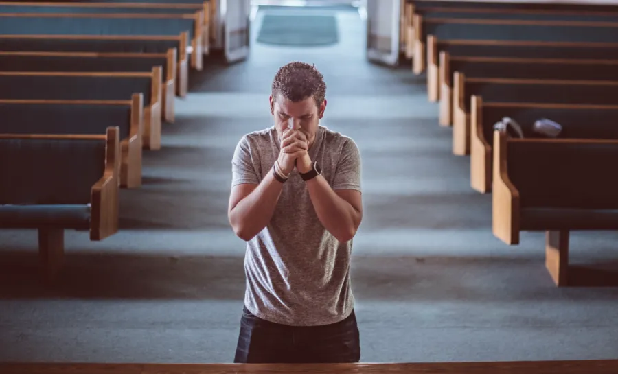 Photo of a man in prayer at the front of an empty church