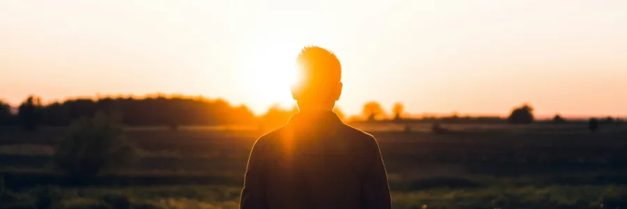 Photo of a man alone looking into the sun