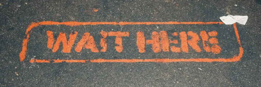Photo of street stenciled with 'wait here'